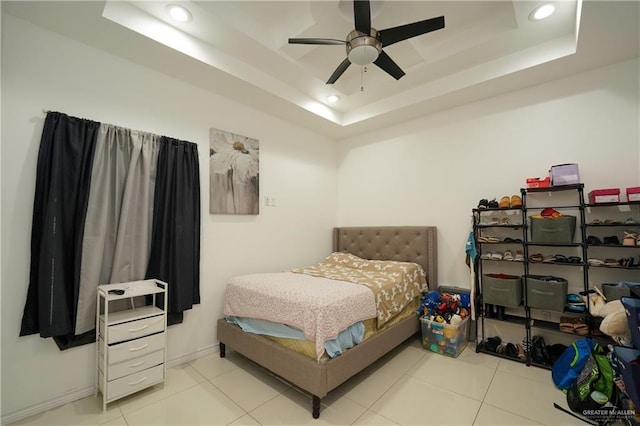 tiled bedroom with a raised ceiling and ceiling fan