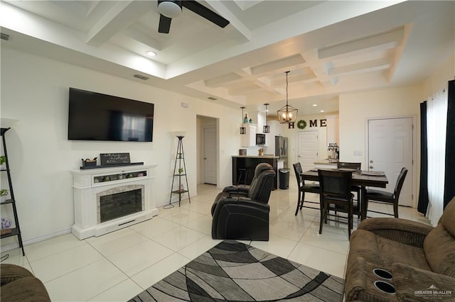 living room with light tile patterned flooring, beamed ceiling, coffered ceiling, ceiling fan, and a premium fireplace