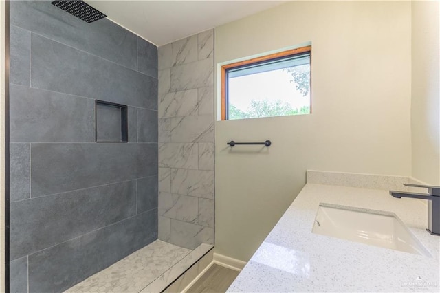 bathroom with hardwood / wood-style flooring, vanity, and tiled shower