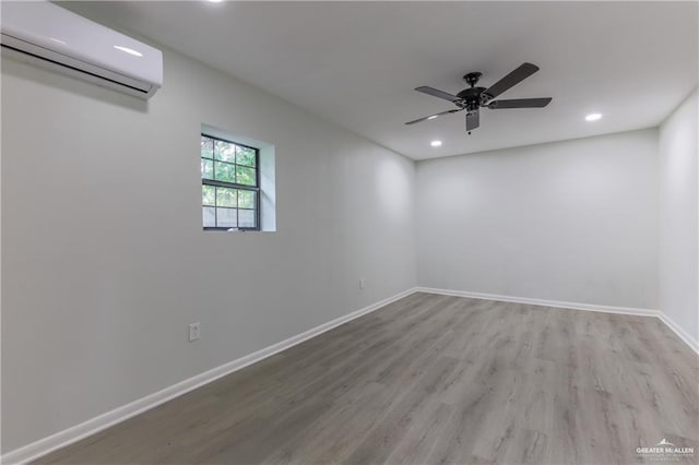 unfurnished room with a wall mounted air conditioner, light hardwood / wood-style flooring, and ceiling fan