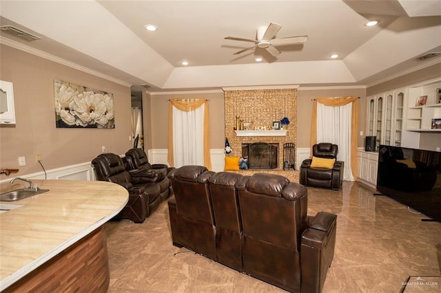 809 N Trosper Rd, Alton, TX 78573 - living room featuring a raised ceiling, ceiling fan, crown molding, wainscoting, and a fireplace