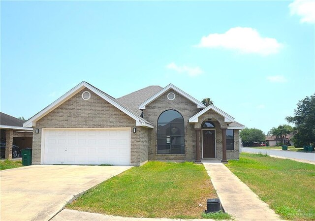 3107 E Laurel St, Hidalgo, TX 78557 - view of front of house with brick siding, a front lawn, a garage, and driveway