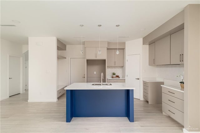 2711 Harmony St, Mission, TX 78574 - kitchen with a sink, decorative backsplash, light wood-type flooring, and an island with sink
