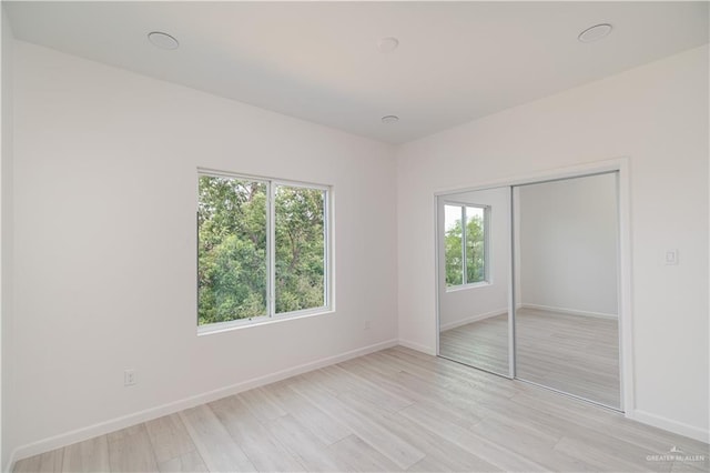 2711 Harmony St, Mission, TX 78574 - unfurnished bedroom with a closet, baseboards, multiple windows, and light wood-style floors