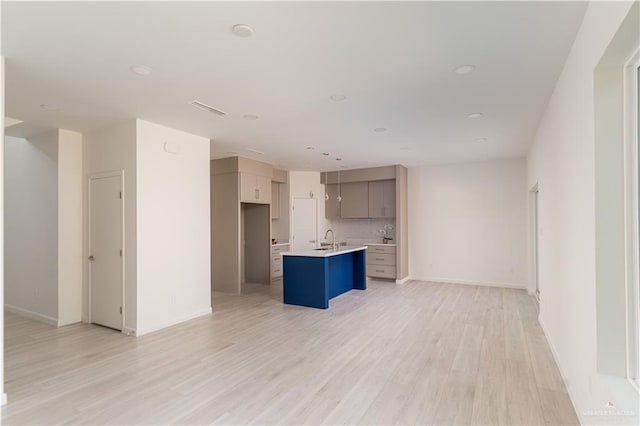 2711 Harmony St, Mission, TX 78574 - unfurnished living room with visible vents, light wood-style floors, baseboards, recessed lighting, and a sink