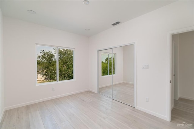 2711 Harmony St, Mission, TX 78574 - unfurnished bedroom featuring a closet, visible vents, multiple windows, and light wood-type flooring