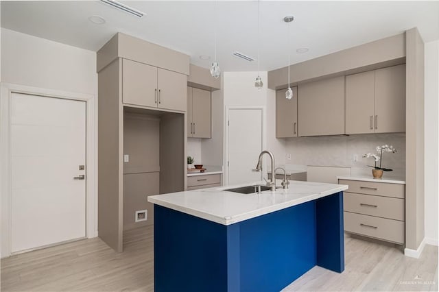 2711 Harmony St, Mission, TX 78574 - kitchen with a center island with sink, light countertops, a sink, light wood-style flooring, and gray cabinetry