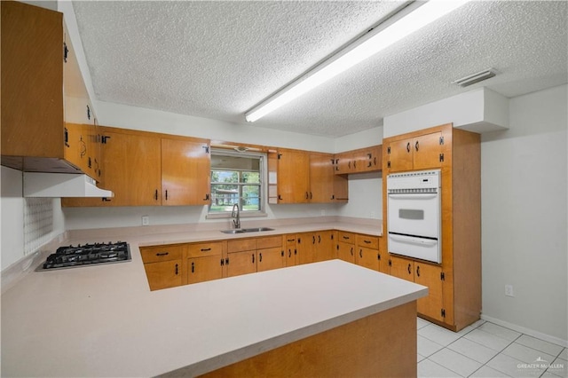 206 E Ricky Crossland Ave, Elsa, TX 78543 - kitchen with a textured ceiling, a peninsula, light countertops, oven, and a warming drawer