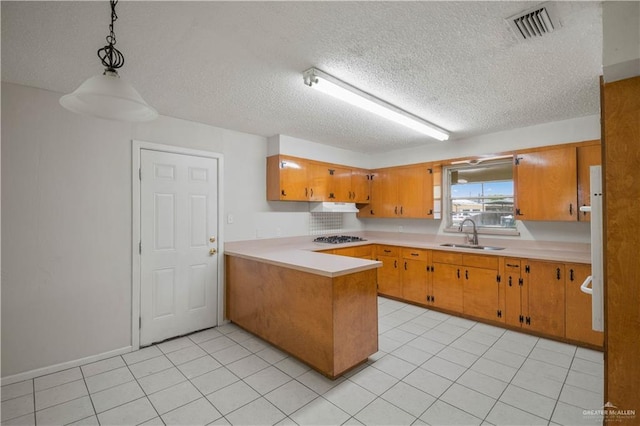 206 E Ricky Crossland Ave, Elsa, TX 78543 - kitchen featuring a peninsula, a textured ceiling, light countertops, brown cabinetry, and light tile patterned floors