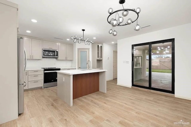 kitchen with light countertops, a chandelier, a sink, light wood-style flooring, and stainless steel appliances