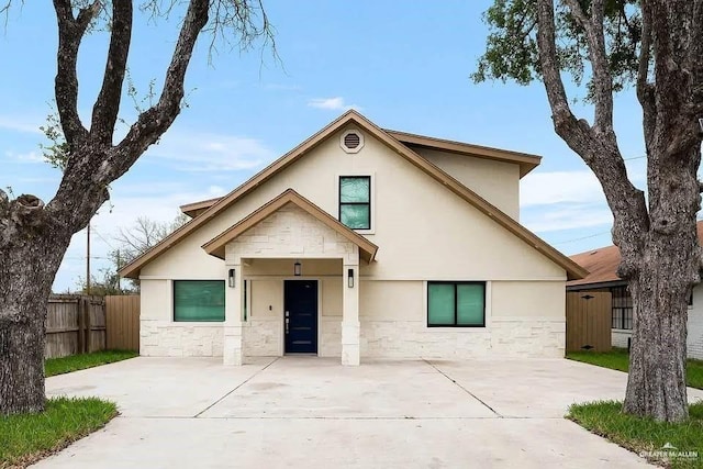 view of front of property featuring fence, stone siding, and stucco siding