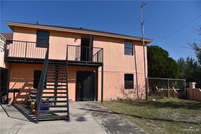 rear view of property featuring a lawn and a balcony