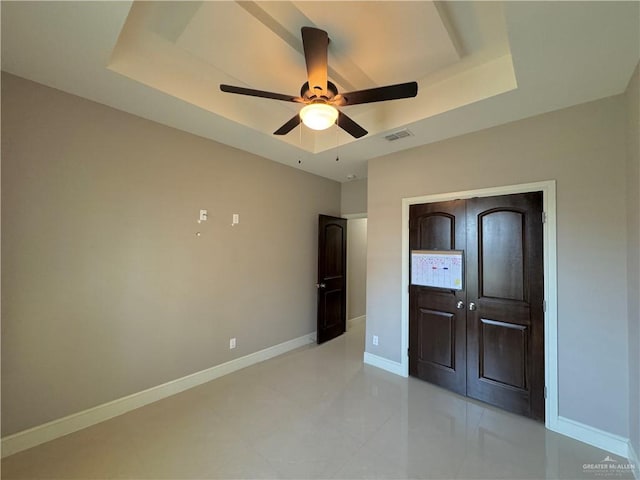 unfurnished bedroom featuring ceiling fan and a raised ceiling