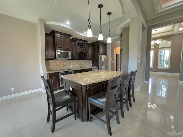 kitchen with decorative backsplash, dark brown cabinets, stainless steel appliances, and decorative light fixtures