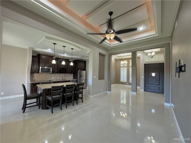 dining area with a raised ceiling, light tile patterned floors, ceiling fan with notable chandelier, and ornamental molding