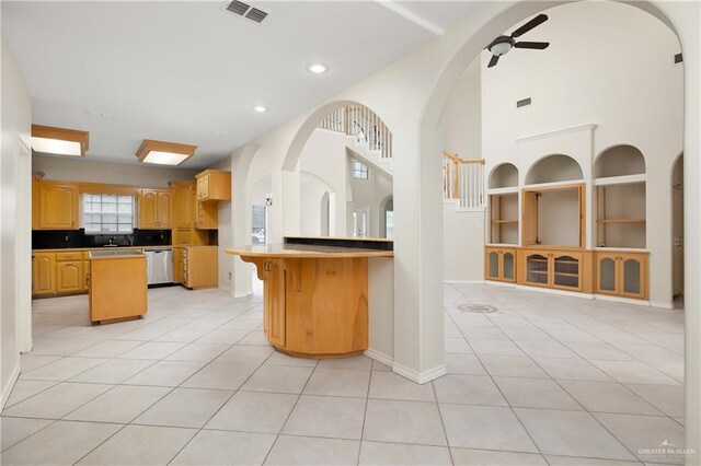 kitchen featuring tasteful backsplash, ceiling fan, light tile patterned floors, dishwasher, and a center island