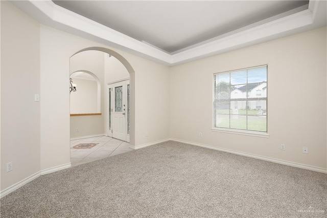 carpeted empty room featuring a tray ceiling