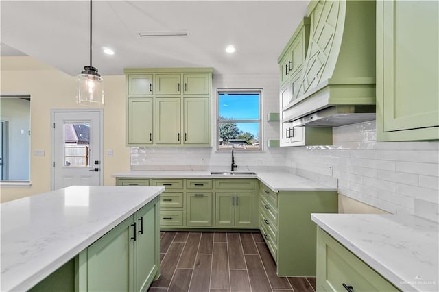 kitchen with light stone countertops, decorative backsplash, sink, decorative light fixtures, and green cabinetry