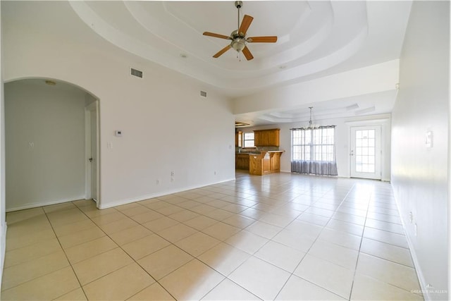 2121 Kingsborough Ave, Mcallen, TX 78504 - unfurnished living room featuring ceiling fan, a tray ceiling, light tile patterned floors, arched walkways, and a chandelier