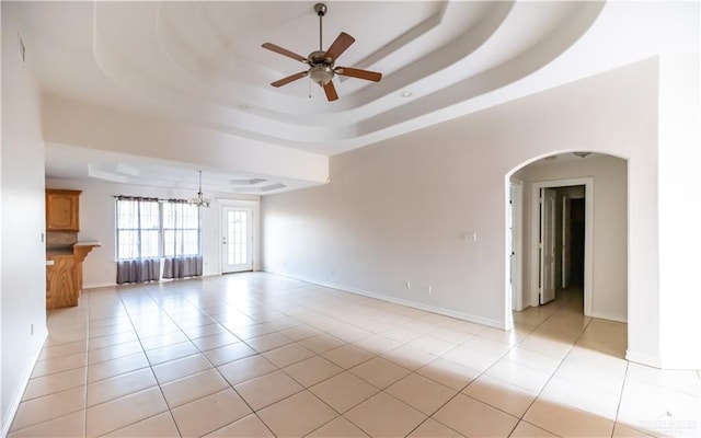 2121 Kingsborough Ave, Mcallen, TX 78504 - unfurnished living room featuring ceiling fan, a raised ceiling, light tile patterned flooring, and arched walkways