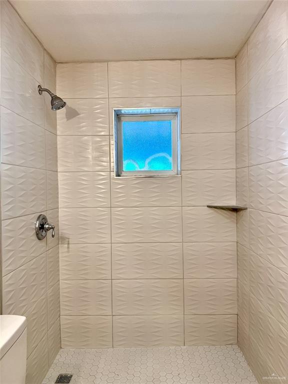 bathroom with tile patterned floors, toilet, and a tile shower
