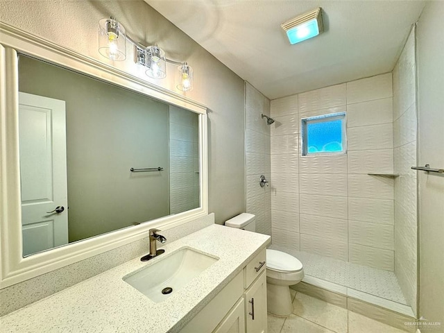 full bathroom featuring tile patterned floors, vanity, toilet, and tiled shower