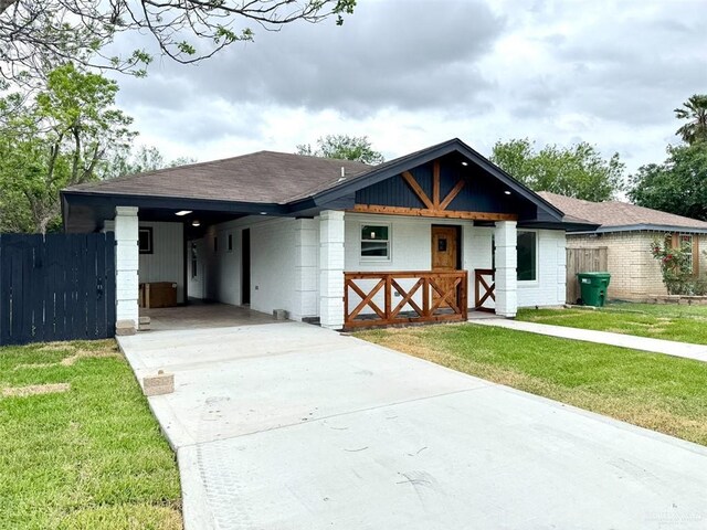 view of front of home with fence, a carport, a front lawn, and concrete driveway