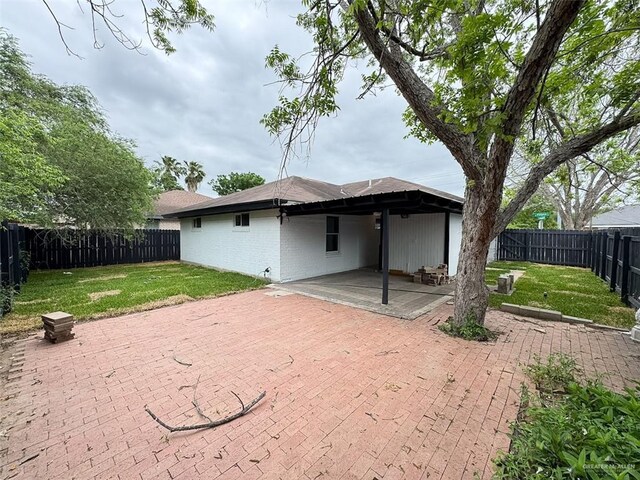 back of house featuring brick siding, a fenced backyard, a patio area, and a lawn