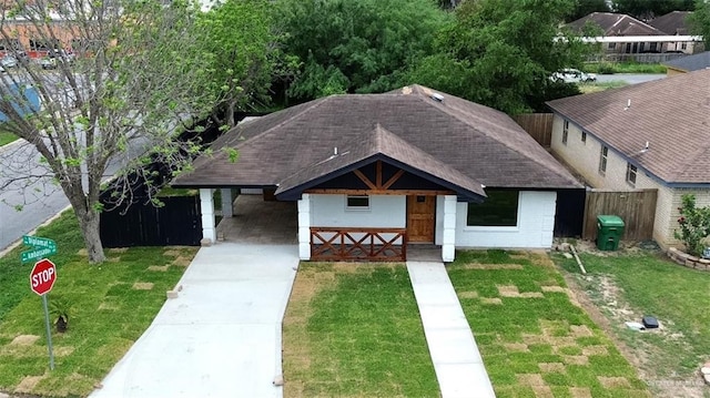 view of front facade with fence, a front yard, driveway, and roof with shingles