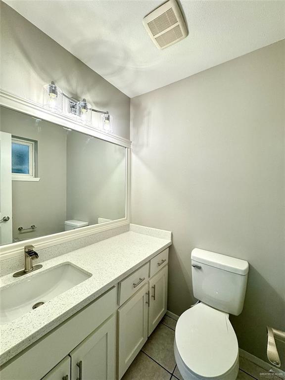 bathroom with vanity, visible vents, toilet, and tile patterned flooring