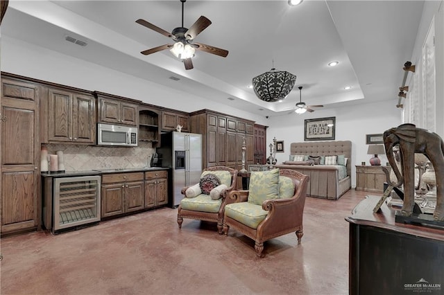 interior space with appliances with stainless steel finishes, backsplash, dark brown cabinetry, a tray ceiling, and beverage cooler