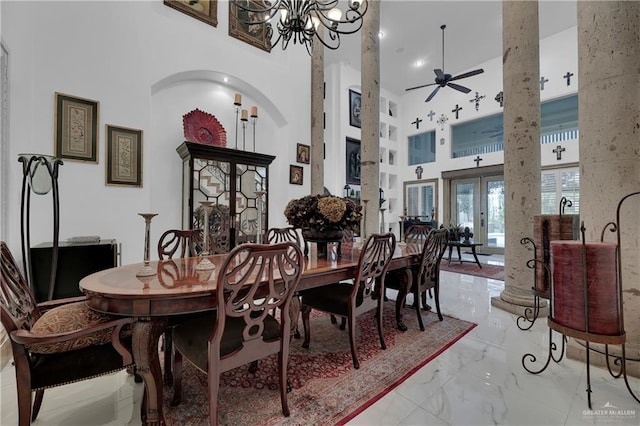 dining area with ceiling fan with notable chandelier, a towering ceiling, and french doors