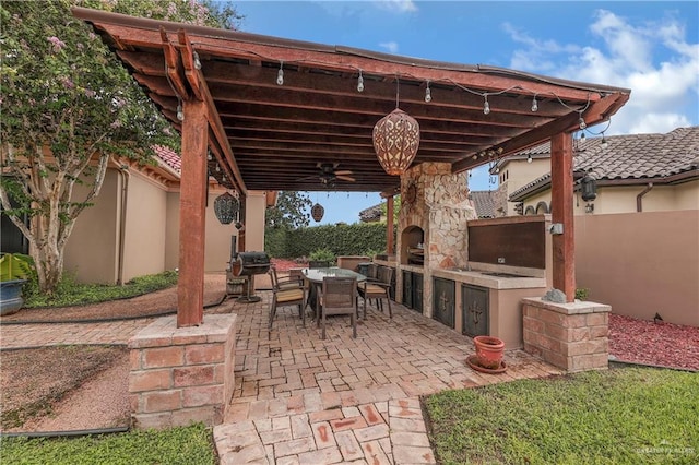 view of patio / terrace with an outdoor kitchen, a stone fireplace, and ceiling fan