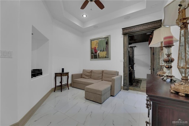 living room with a tray ceiling and ceiling fan