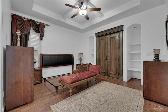 sitting room featuring a tray ceiling, ceiling fan, built in features, and light hardwood / wood-style floors