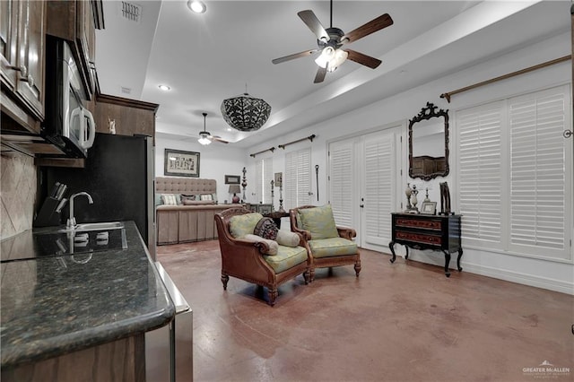 living room featuring concrete flooring and a tray ceiling