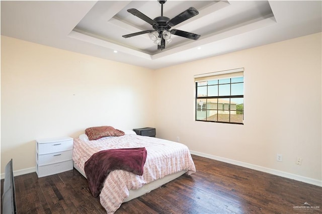 bedroom featuring a raised ceiling, ceiling fan, and dark wood-type flooring