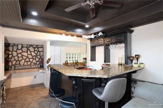 kitchen featuring a kitchen breakfast bar, kitchen peninsula, light stone counters, and sink