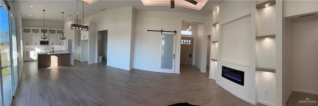 unfurnished living room featuring a healthy amount of sunlight, a barn door, and a towering ceiling