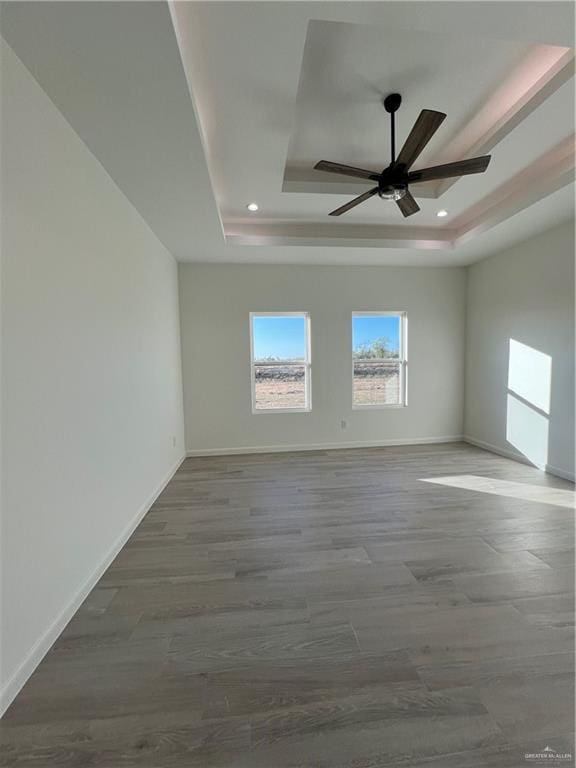 unfurnished room with ceiling fan and a tray ceiling