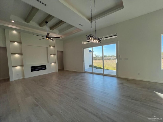 unfurnished living room featuring hardwood / wood-style flooring, ceiling fan, a tray ceiling, and beamed ceiling