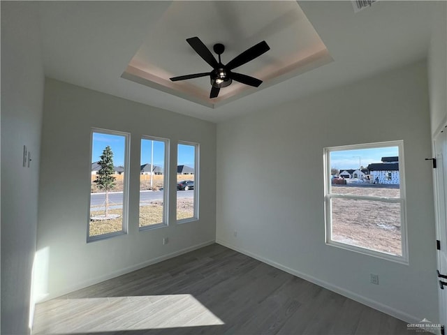 unfurnished room featuring ceiling fan, dark hardwood / wood-style flooring, and a raised ceiling