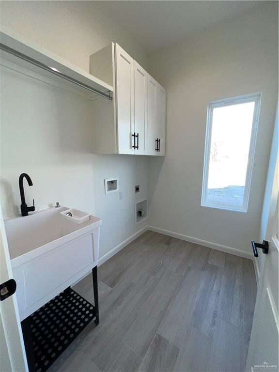 laundry room featuring hookup for a washing machine, light wood-type flooring, hookup for an electric dryer, and cabinets