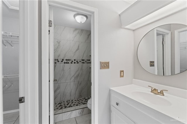 bathroom featuring tile patterned flooring, a tile shower, vanity, and toilet