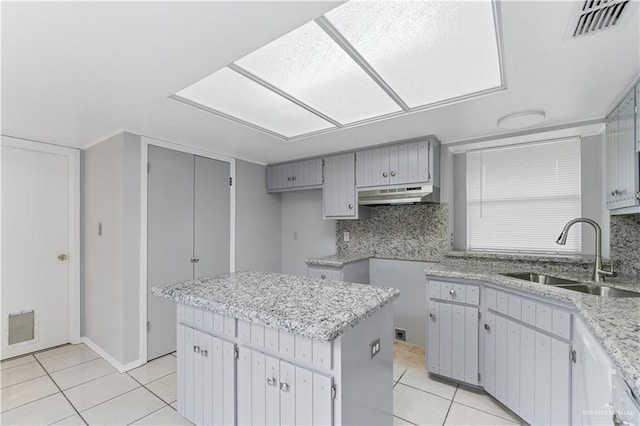 kitchen featuring decorative backsplash, light tile patterned flooring, sink, a kitchen island, and range hood