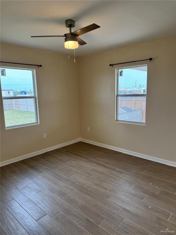 spare room featuring ceiling fan, baseboards, and wood finished floors