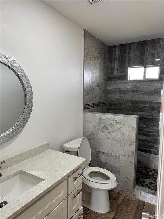 full bath featuring a walk in shower, toilet, vanity, and wood tiled floor