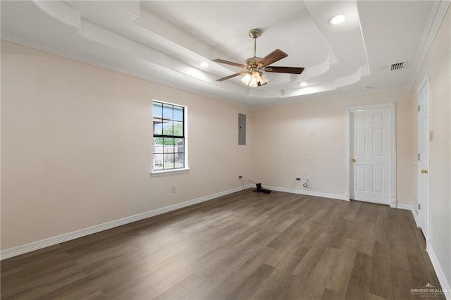 spare room featuring ceiling fan, electric panel, a tray ceiling, hardwood / wood-style flooring, and ornamental molding