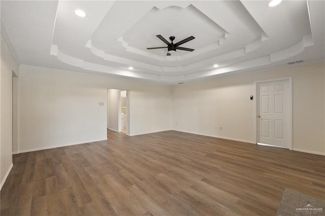 spare room featuring dark hardwood / wood-style flooring, ceiling fan, a raised ceiling, and crown molding