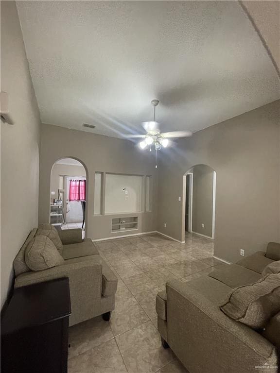 tiled living room with a textured ceiling and ceiling fan